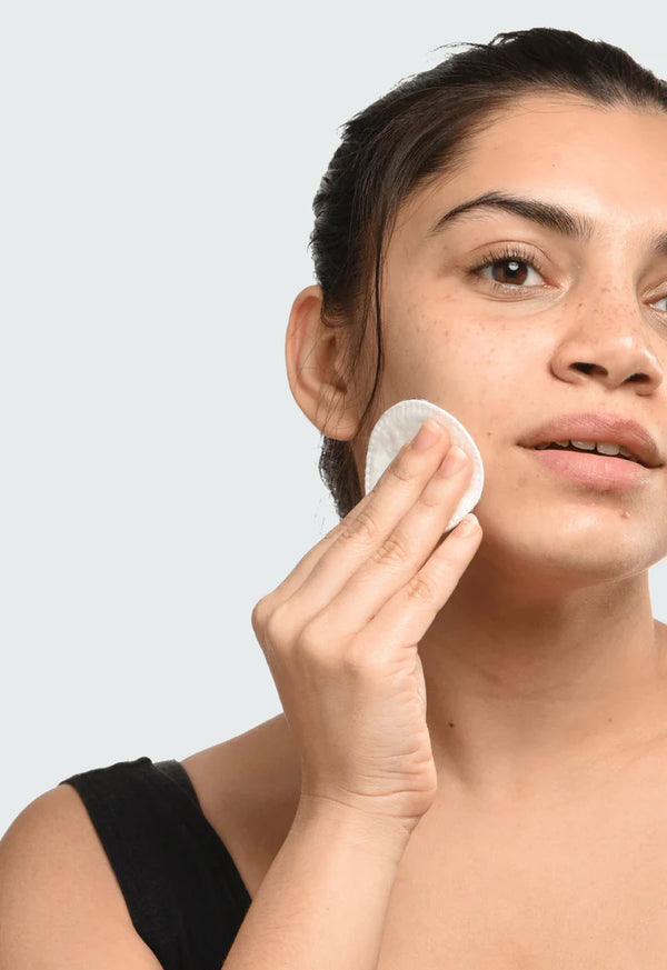 a women using a cotton pad to apply Minimalist Polyhydroxy Acid (PHA) 03% Toner to her cheek