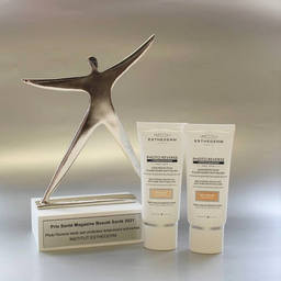 two Institut Esthederm Photo Reverse High Protection Tinted Light Beige tubes placed next to an award