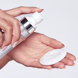 Hand holding a skincare product with a white background