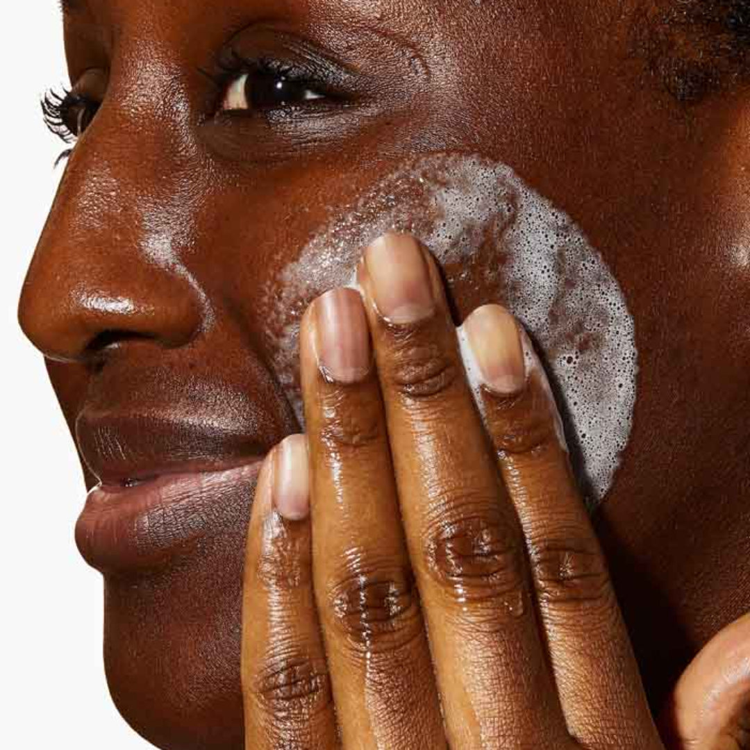 Model applying CeraVe SA Smoothing Cleanser 236ml to their face