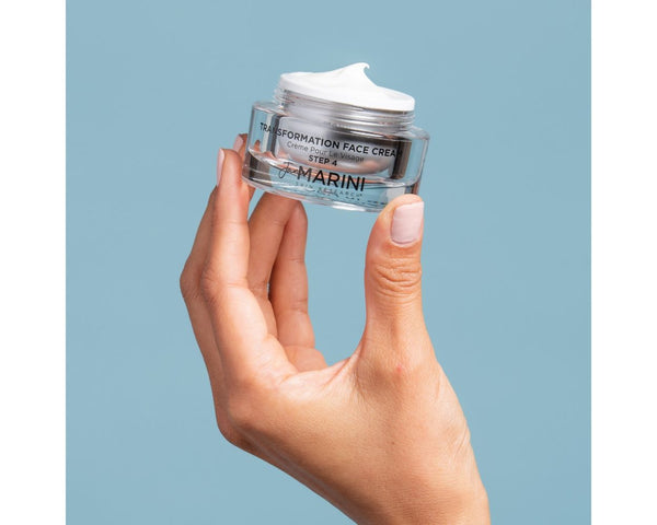 A jar of Jan Marini Transformation Face being held in the air with a blue background