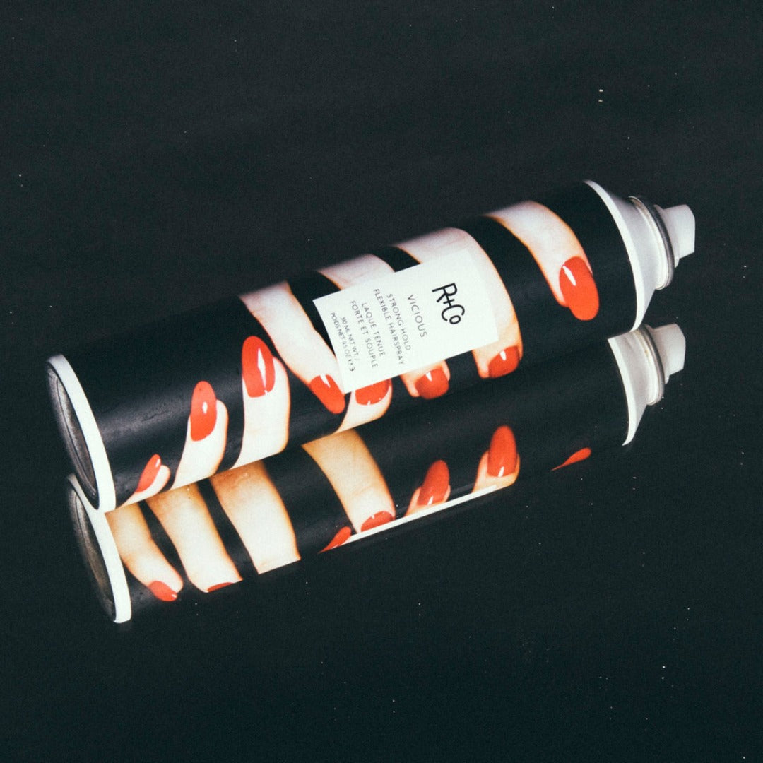 R+Co Vicious Strong Hold Flexible Spray on a dark reflective surface
