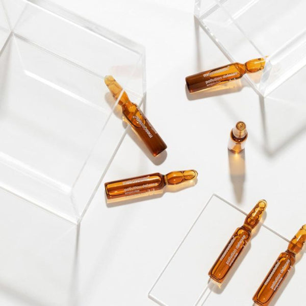 6 vials of mesoestetic Pollution Defense Ampoules in and on top of glass boxes