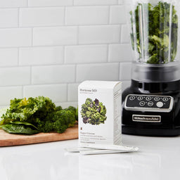 Perricone MD Super Greens 30's Kit with green vegetables in a blender and chopping board
