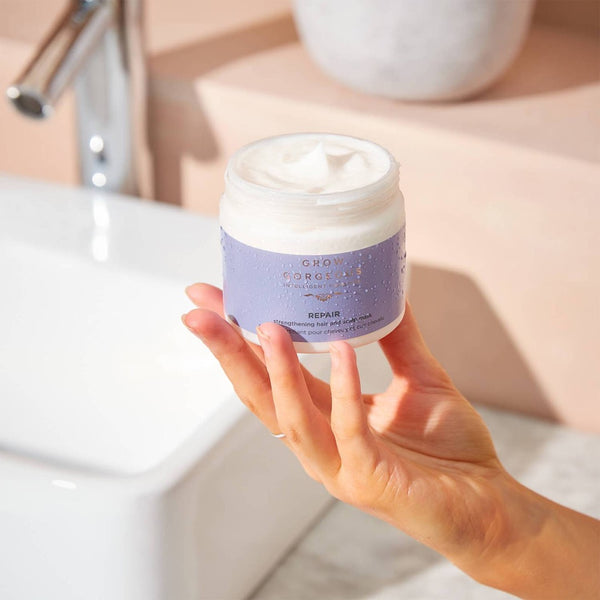 a tub of Grow Gorgeous Repair Strengthening Hair & Scalp Mask held in the palm of their hand