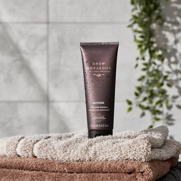 Grow Gorgeous Intense Thickening Shampoo tube on a stack of towels