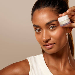 a women holding a tub of ESPA Tri-Active Resilience Pro Biome Eye Treatment close to her face
