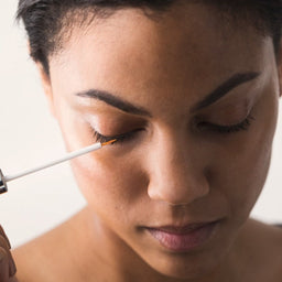 a woman applying the serum to her eye lashes