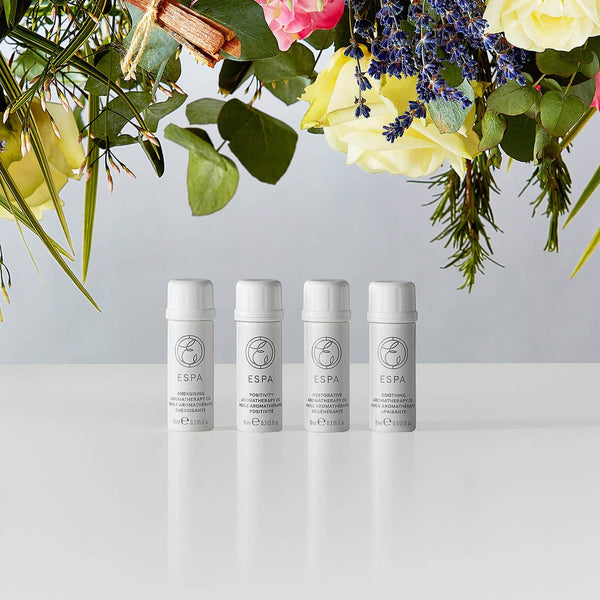 ESPA Aromatherapy Essential Oil Blend Collection with flowers towering over the bottles