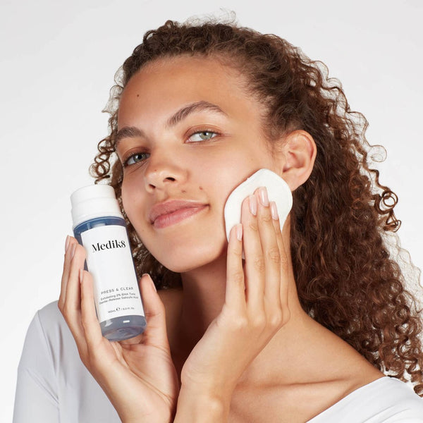 a model holding a bottle of Medik8 Press & Clear close to her face