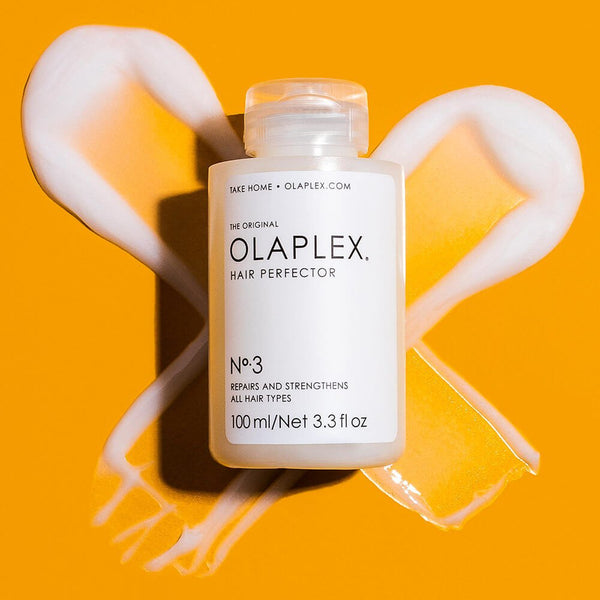 Olaplex No.3 Hair Perfector bottle on top of the texture in the shape on an X