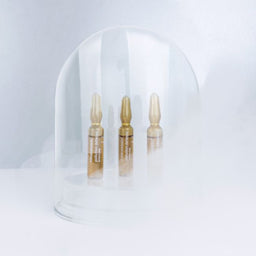 3 vials of mesoestetic Pollution Defense Ampoules in a glass dome with mist outside it