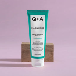 Q+A Niacinamide Exfoliating Cleanser in front of a wooden block