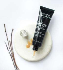 Institut Esthederm Intensive Propolis+ Concentrate Serum Tube on a marble coaster with serum spread around it