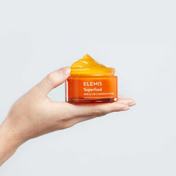 Elemis Superfood AHA Glow Cleansing Butter Facial Cleanser held in a palm of a hand