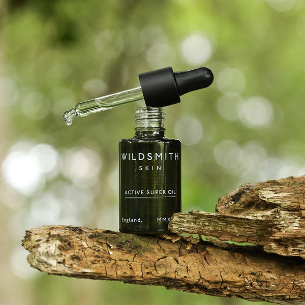 Wildsmith Skin Active Super Oil 30ml with full pipette drop on a tree trunk