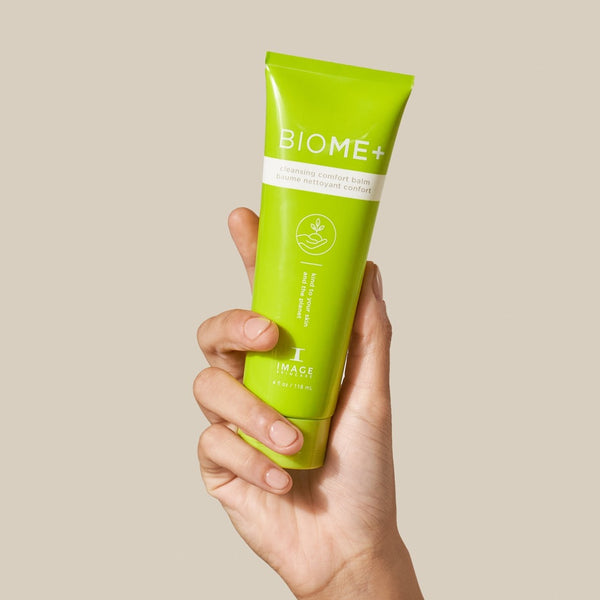 model holding the Image Skincare BIOME+ Cleansing Comfort Balm tube