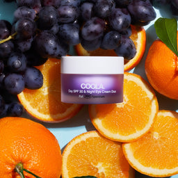 COOLA Day SPF30+Night Eye Cream Duo tub on top of a range of fruit