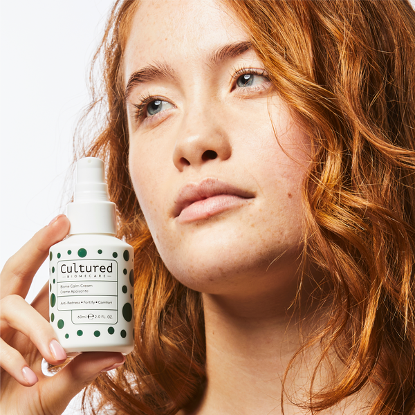 A model holding a bottle of cultured biomecare close to her face