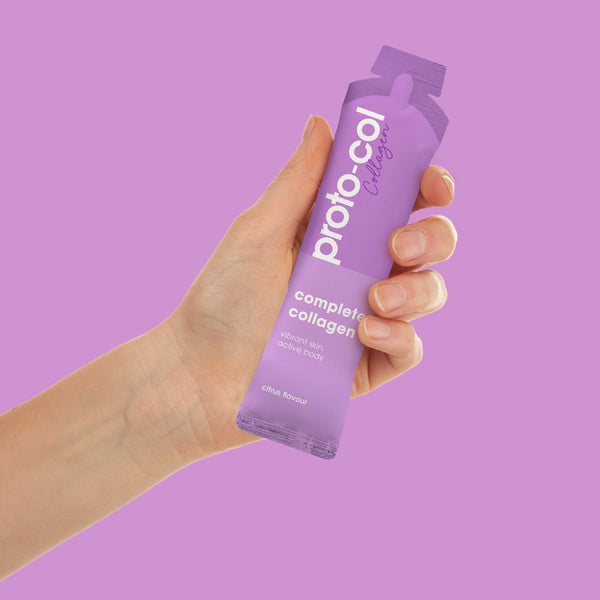 a hand holding a sachet of Proto-col Complete Collagen