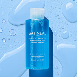 A bottle of Gatineau Floracil Eye Makeup Remover with large droplets of water around it