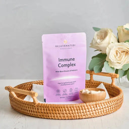 Rejuvenated Immune Complex packet on a woven tray and cup of capsules