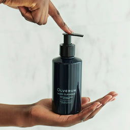 Olverum Body Cleanser 250ml held in the palm of a hand
