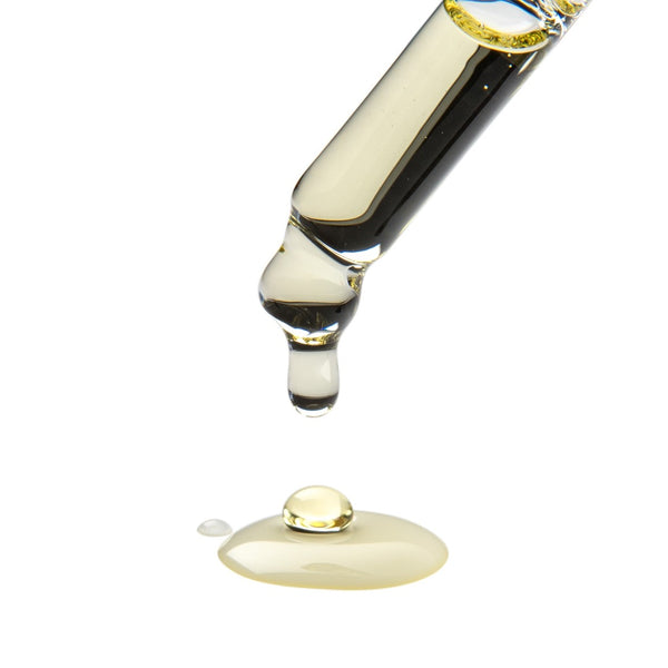 a pipette dripping the facial oil onto a white surface