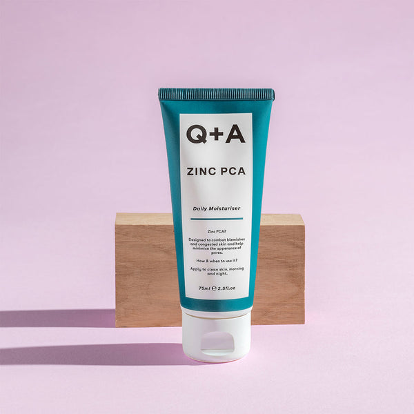 Q+A Zinc PCA Daily Moisturiser in front of a wooden slab