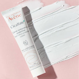Avène Cicalfate + Restorative Protective Cream for Very Sensitive Skin poured onto a pink surface