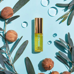 COOLA Classic Liplux Oil amongst a range of leaves and plants