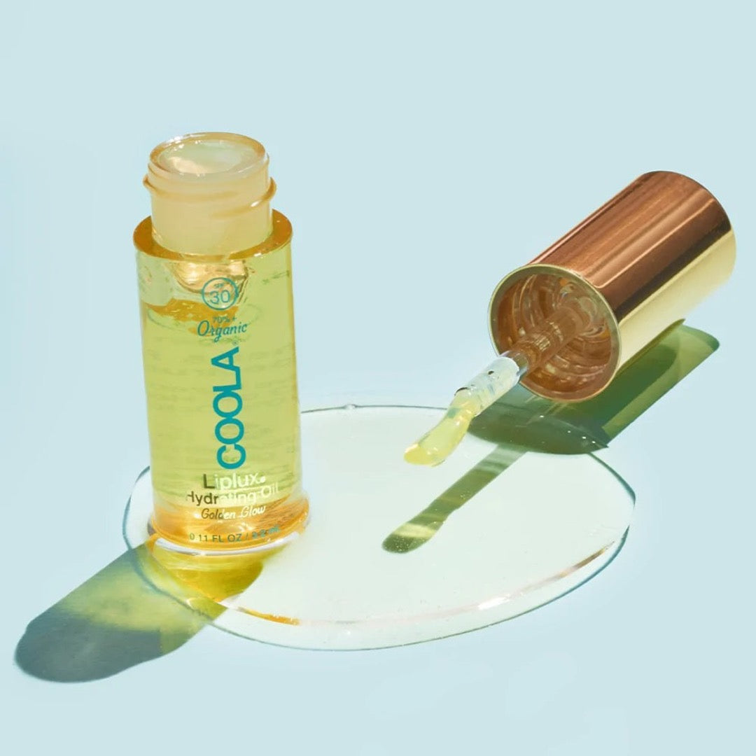 COOLA Classic Liplux Oil poured onto a blue surface