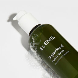 Elemis Superfood Facial Wash bottle laid on its side covered in soap suds
