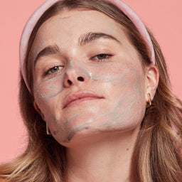 a close up of a women applying cleanser to her face