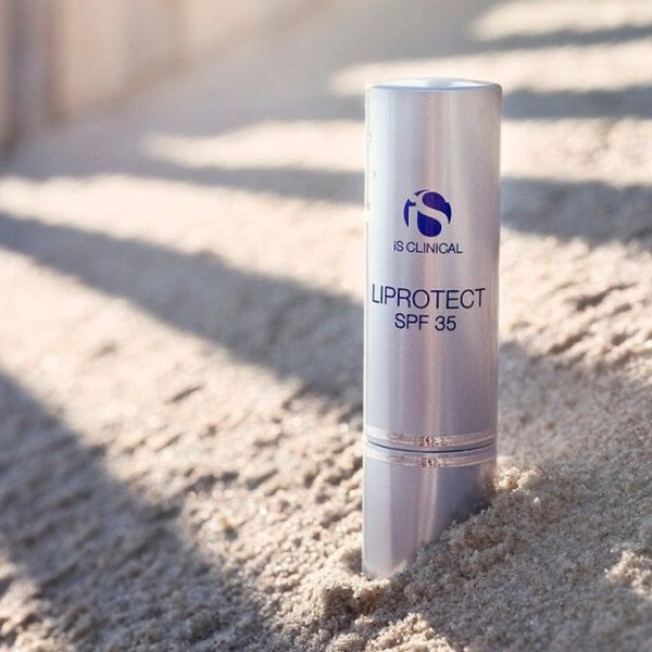 iS Clinical Liprotect SPF 35 placed in the sand on a beach