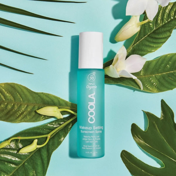 COOLA Makeup Setting Spray SPF30 on top of a bed of flowers