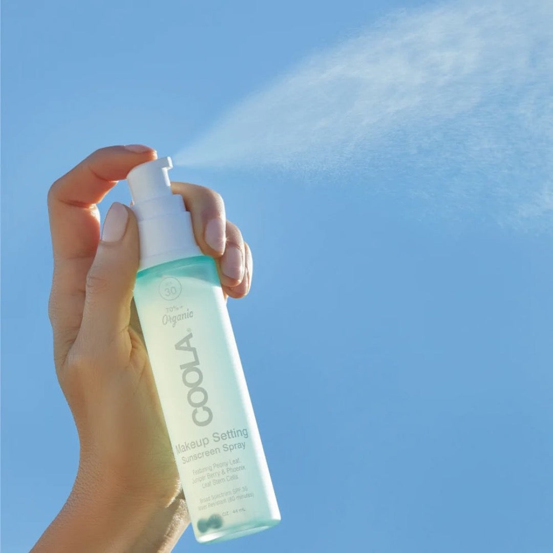Model spraying COOLA Makeup Setting Spray SPF30