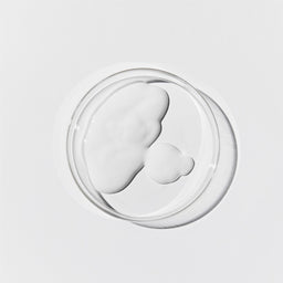 Aerial shot of the cleansing milk. It's an opaque, white liquid in a petri dish against a white background.