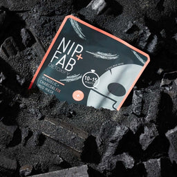 Nip+Fab Charcoal Fix & Mandelic Acid Purifying Sheet Mask packaging tucked into a pile of charcoal 