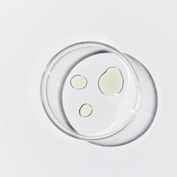 Aerial shot of a petri dish with 3 pools of translucent yellow liquid against a white background.