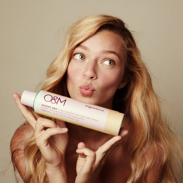 a model holding O&M Desert Dry Texture Spray close to her face