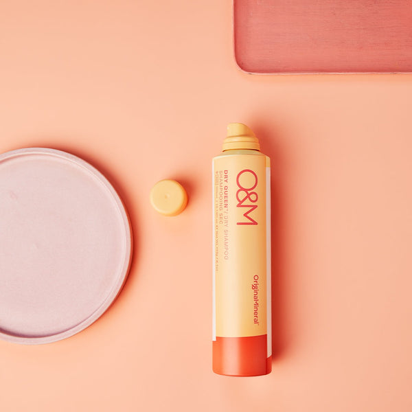 O&M Dry Queen Dry Shampoo bottle on a salmon pink surface