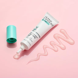 White clear skin tube with light blue lid and gel squiggled next to the tube on pink table