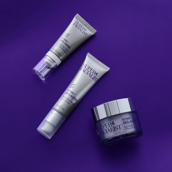 Retinol anti-ageing eye cream next to a serum next to day cream jar on purple background