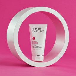 Creamy cleanser tube inside a white circular prop  against a bright pink backdrop