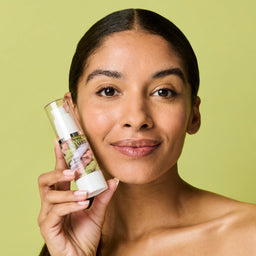 Model holding the primer next to her face while looking into the camera lens