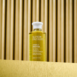 Vitamin C cleansing oil bottle on gold table and gold background